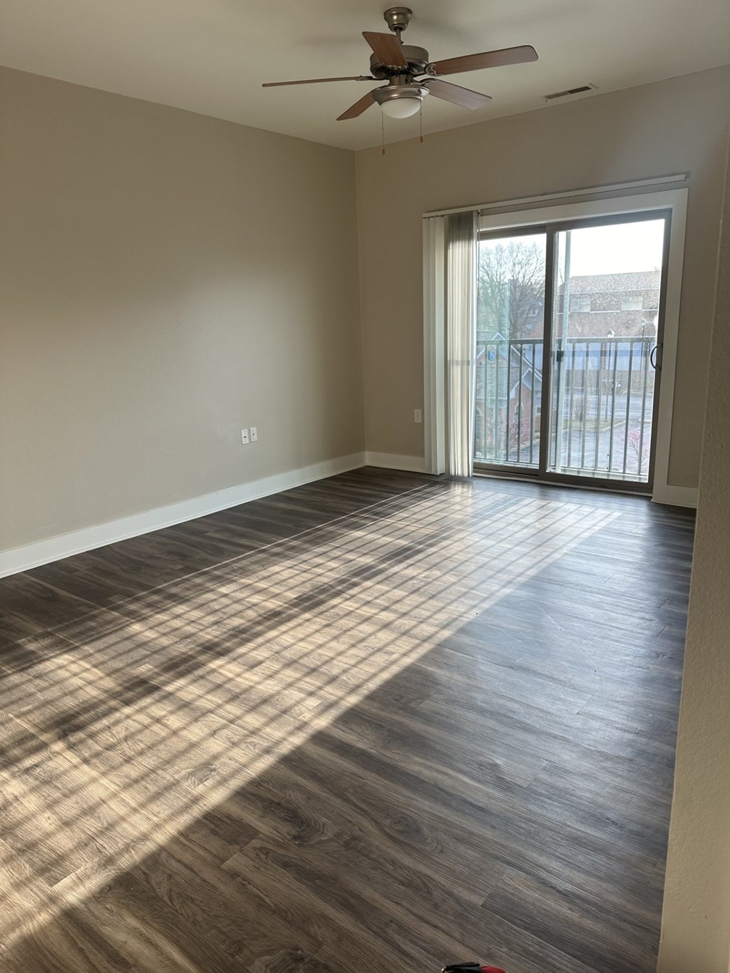 A room with a ceiling fan and sliding glass doors.