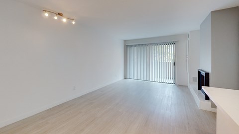 a living room and dining room with white walls and wood flooring