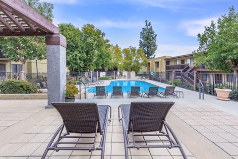 Two chairs are placed on a patio in front of a pool.