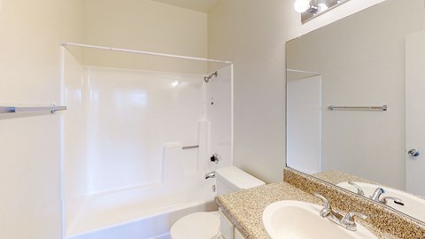 A white bathroom with a sink, mirror, and shower.