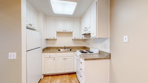 A kitchen with white cabinets and a white dishwasher.
