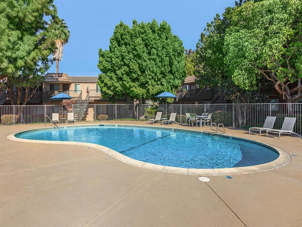 a resort style swimming pool with chairs and umbrellas