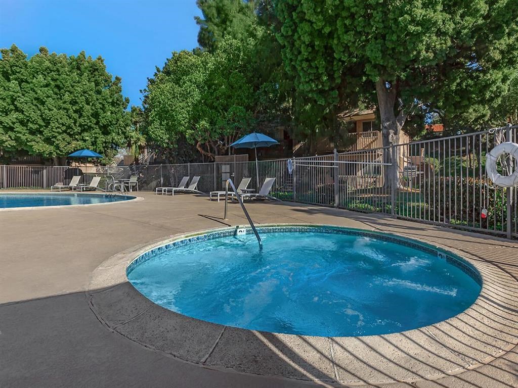 a blue pool with chairs and umbrellas near a fence