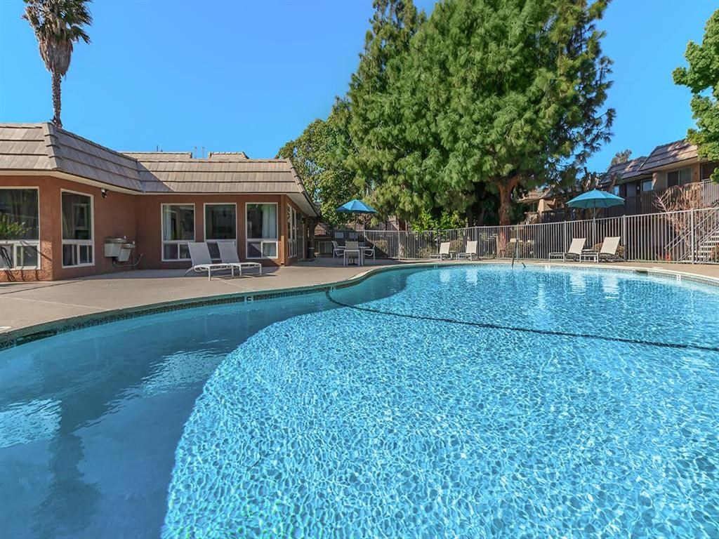 a swimming pool with a house and trees in the background
