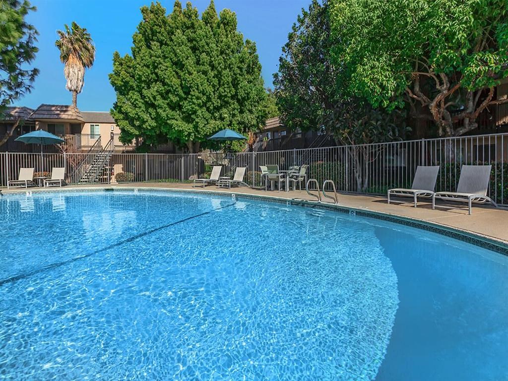 a large pool with chairs and umbrellas at a resort pool