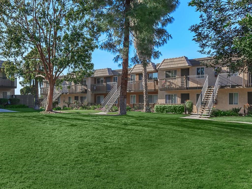 an exterior view of an apartment building with green grass and trees