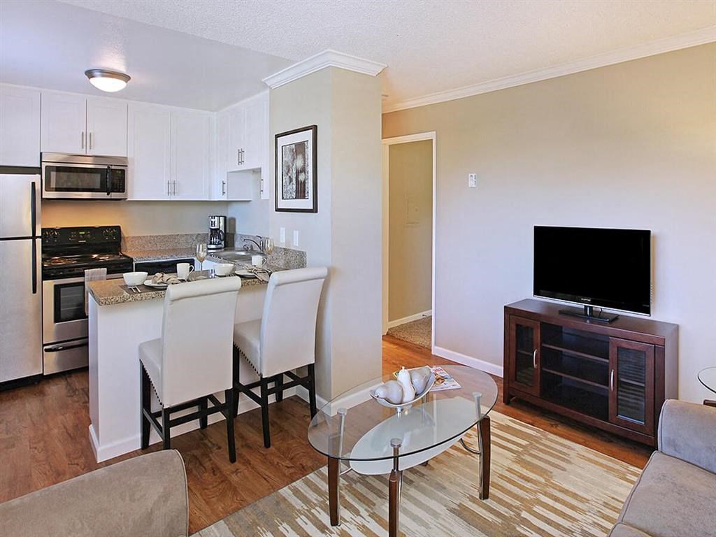 a living room and kitchen with a table and a television