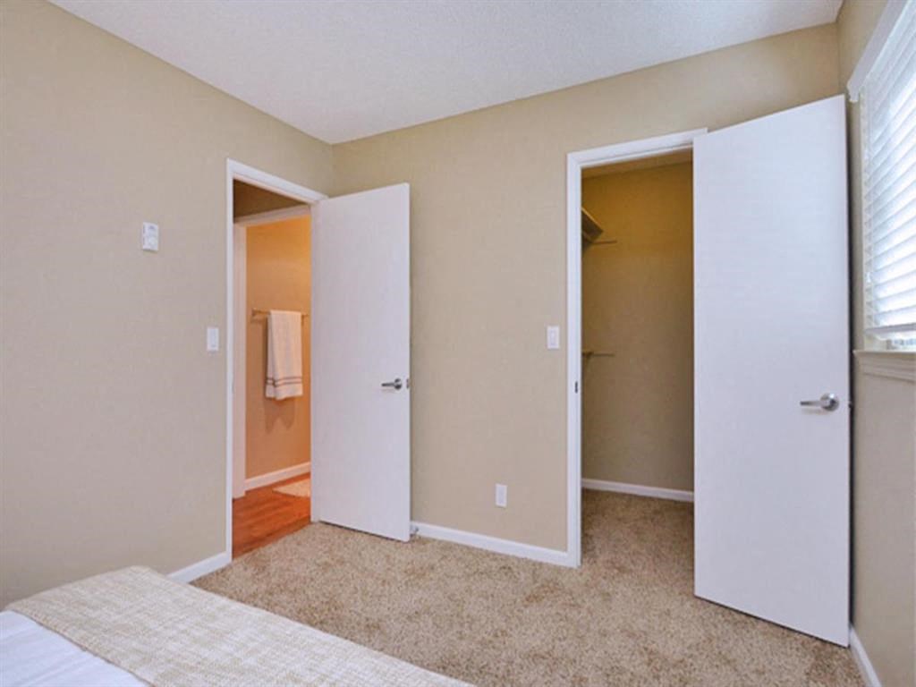 a bedroom with an open door to a bathroom and a closet