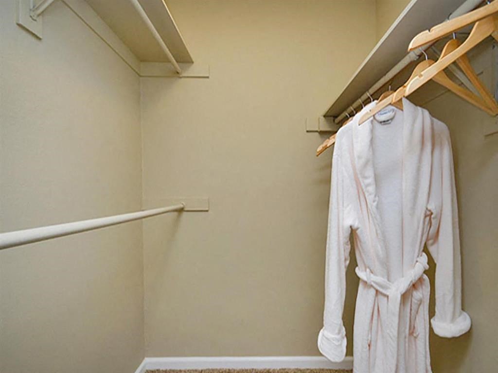 a white robe hanging in a closet next to a towel rack