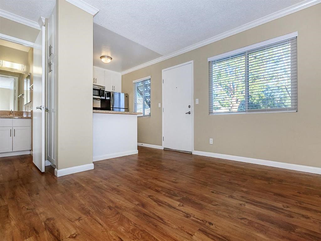 an empty living room and kitchen with wood floors