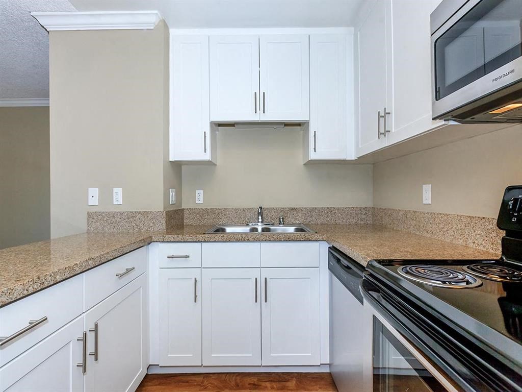 a kitchen with white cabinets and a stove and a sink