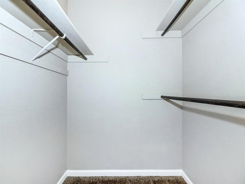 a walk in closet with white walls and a hanging rack