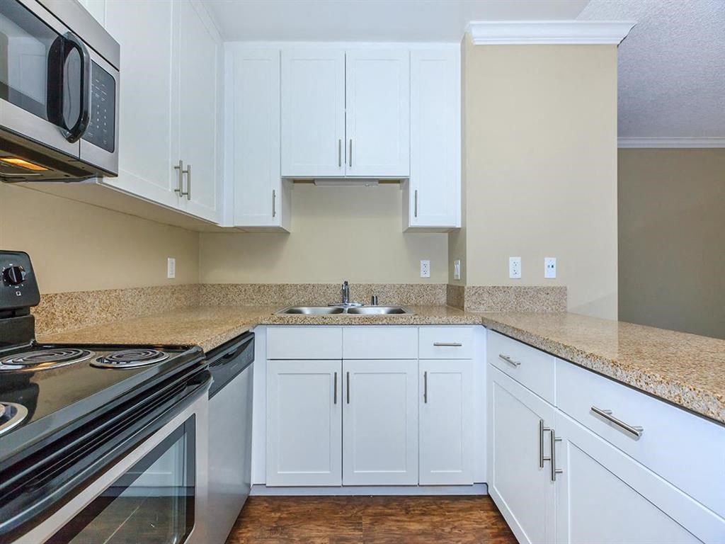 a kitchen with white cabinets and a stove and a sink