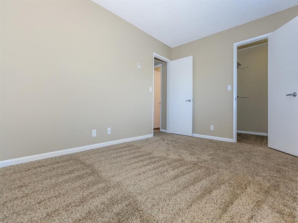 an empty living room with carpet and a door to a closet