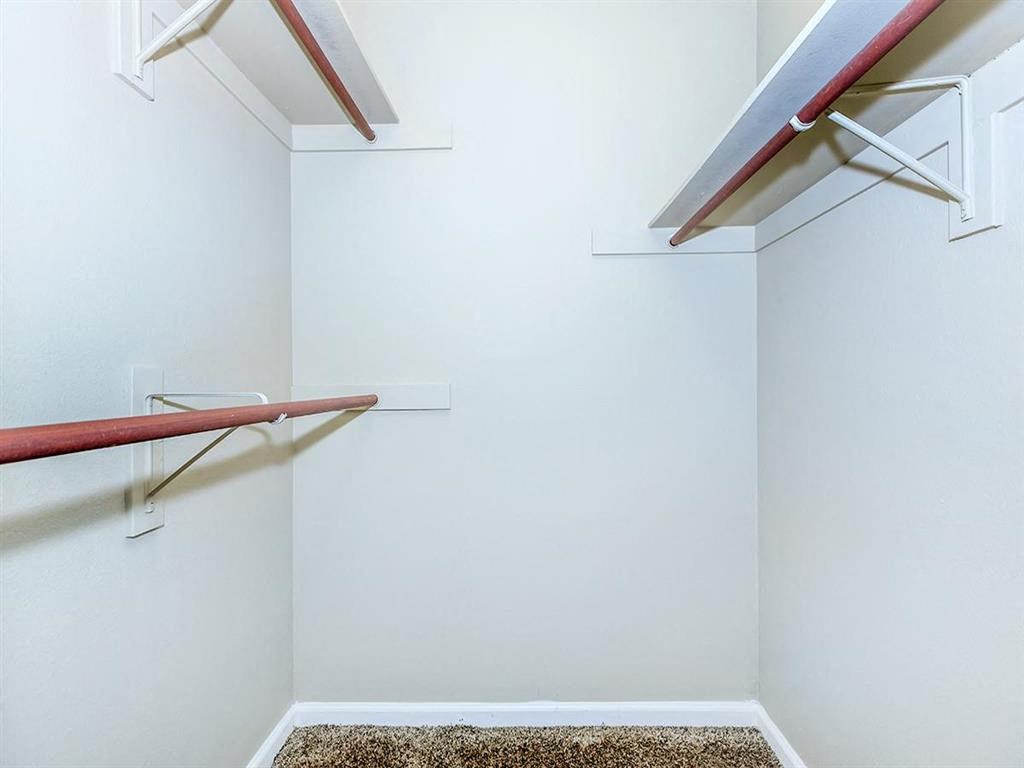 a walk in closet with white walls and a closet with shelves