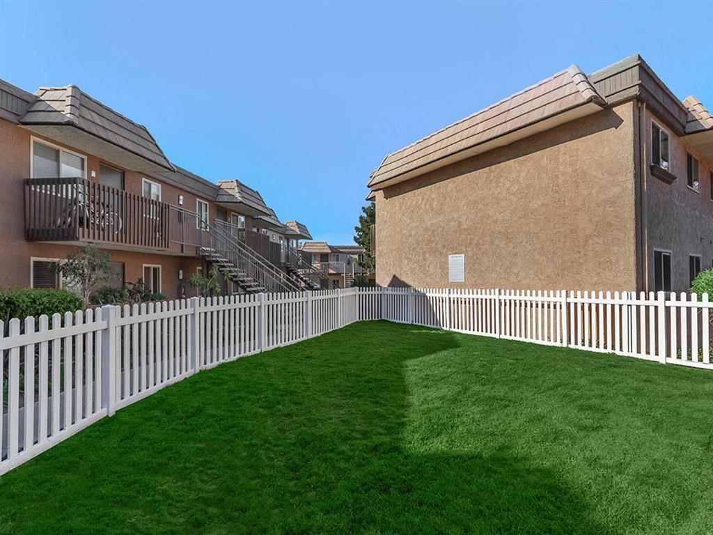 a yard with a white fence in front of some apartments