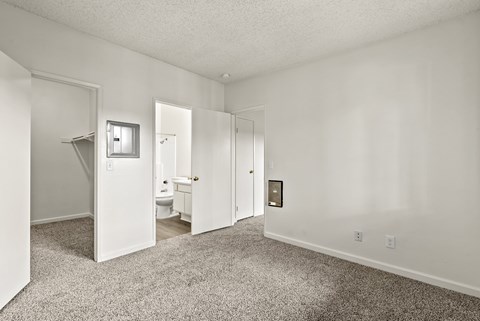 A white bedroom with a carpeted floor and a white door.