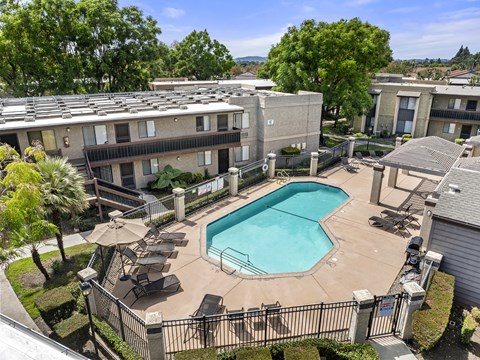 A swimming pool surrounded by a black fence and chairs.