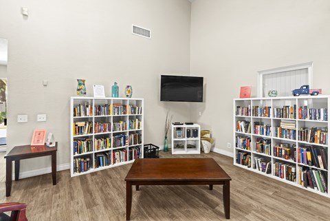 A living room with a brown table and a bookshelf filled with books.