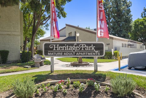 A sign for Heritage Park Mature Adult Apartments is displayed in front of a building.