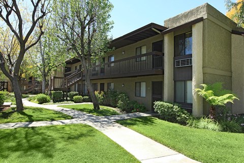 A building with a balcony and a tree in front of it.