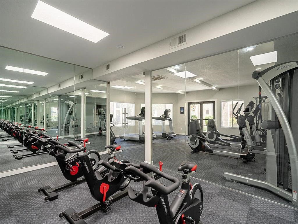 a gym with various exercise equipment and mirrors