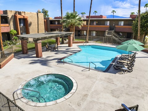 A pool with a hot tub and a table with chairs.