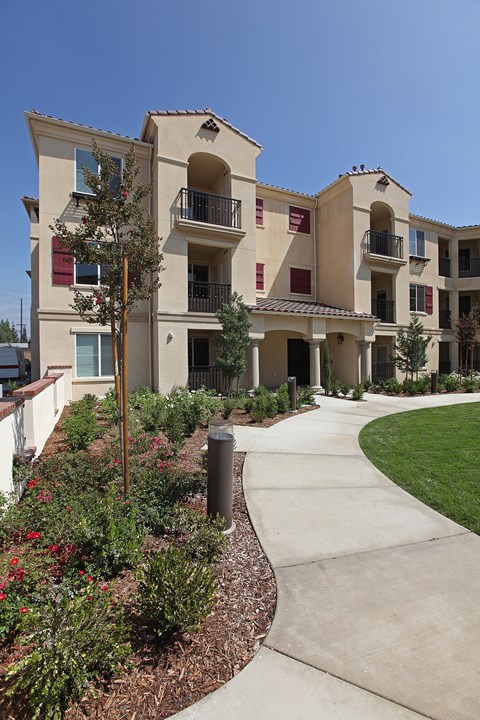 Apartment complex with a walkway and landscaping.