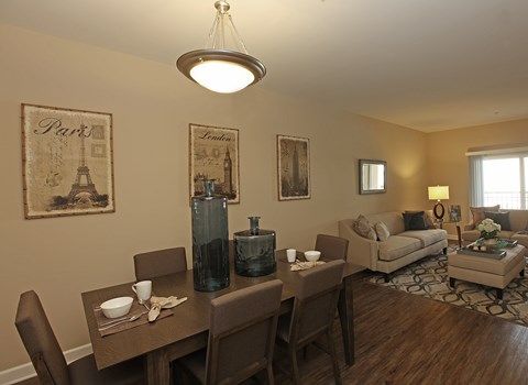 A dining room with a table set for two and a couch in the background.