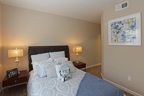 A bedroom with a large bed and two lamps on side tables.