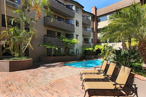 a pool with chairs in front of an apartment building