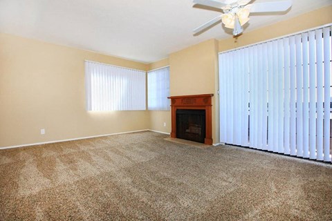 an empty living room with a fireplace and a ceiling fan