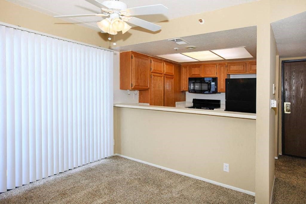 a living room with a kitchen and a ceiling fan