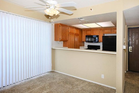 a living room with a kitchen and a ceiling fan