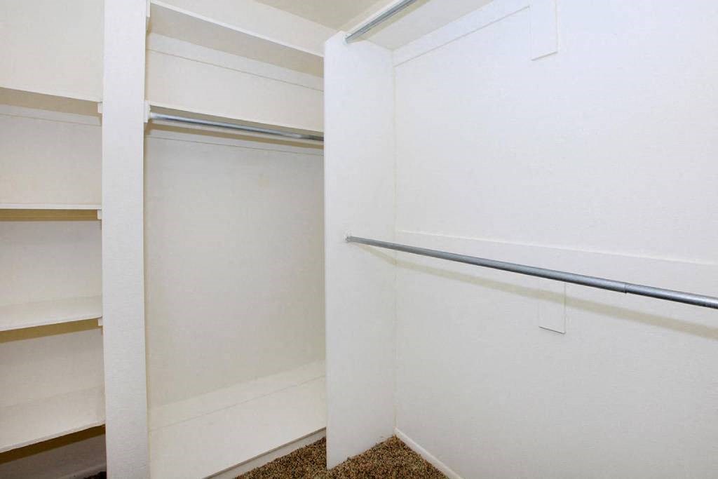 a walk in closet with white cabinets and a glass door