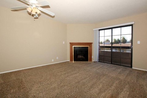 an empty living room with a fireplace and a ceiling fan