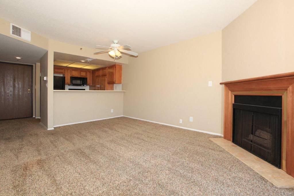 an empty living room with a fireplace and a ceiling fan