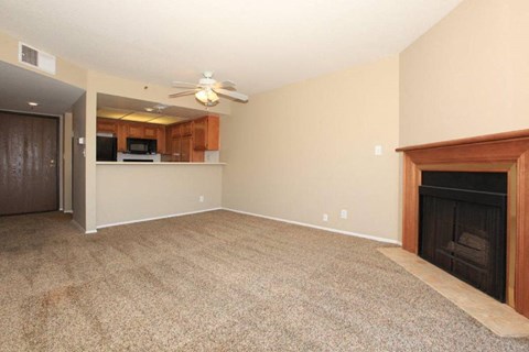 an empty living room with a fireplace and a ceiling fan