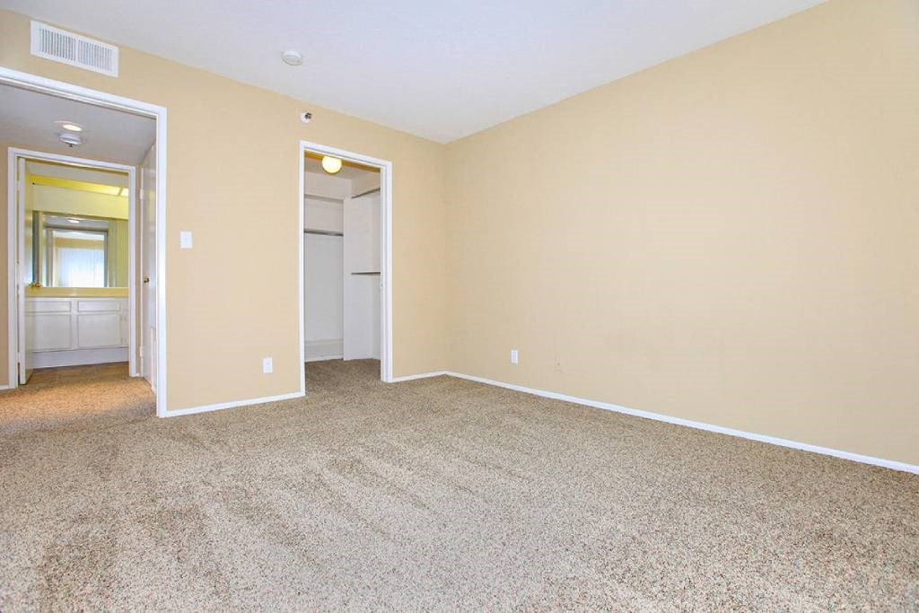 an empty living room with carpet and a door to a bathroom