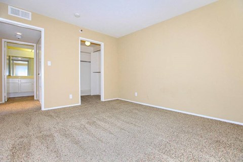 an empty living room with carpet and a door to a bathroom