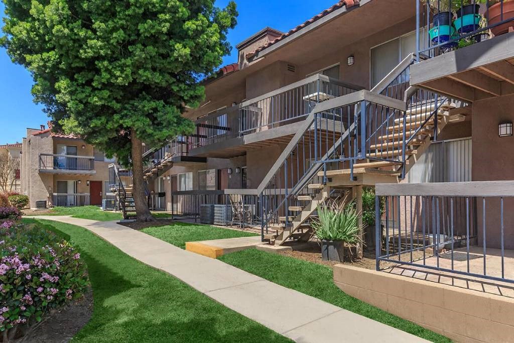 an apartment building with stairs and grass and trees