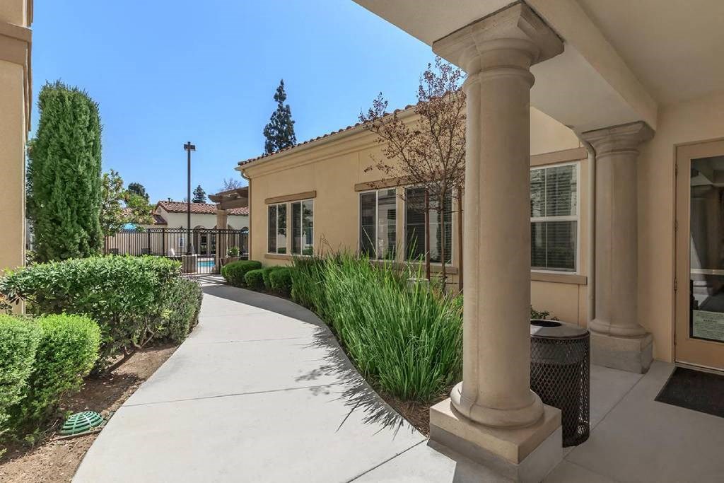 a sidewalk in front of a building with a column