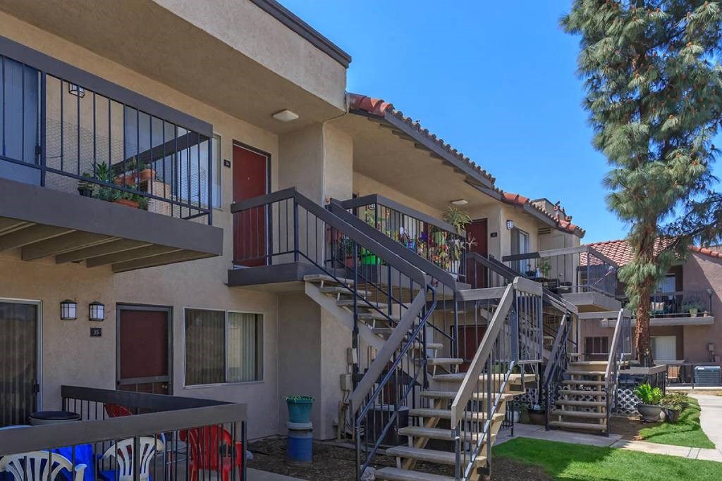 an apartment building with stairs and balconies and trees