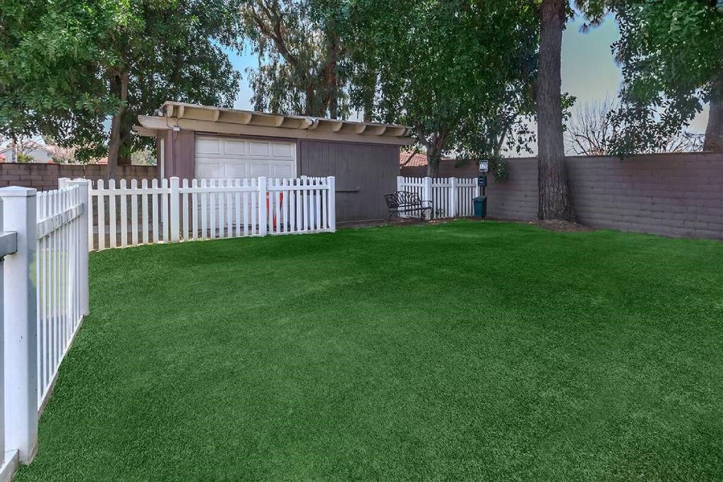 a yard with green grass and a white fence