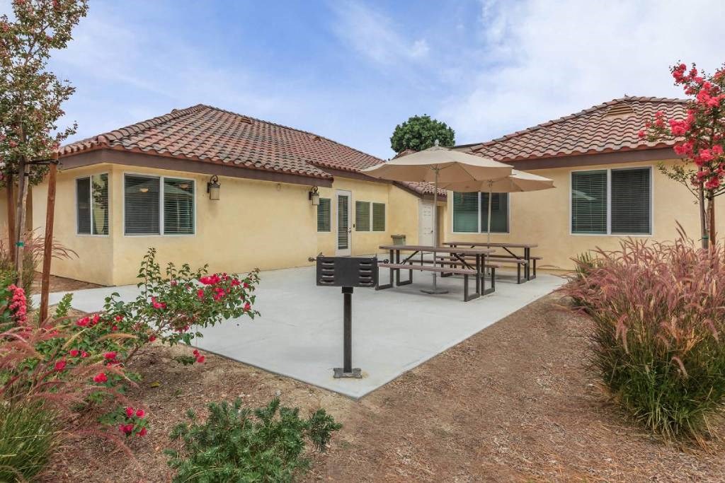 a patio in front of a house with a table and umbrella