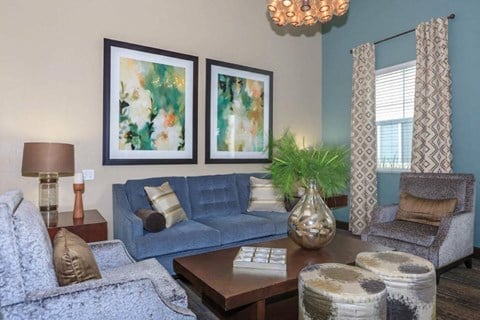 a living room with a blue couch and two paintings on the wall