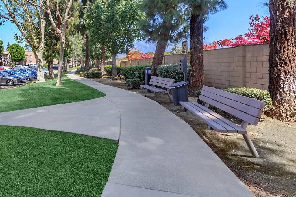 two benches sitting next to a sidewalk in a park
