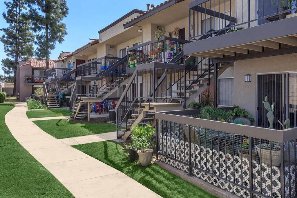 a row of apartments with stairs and balconies and grass