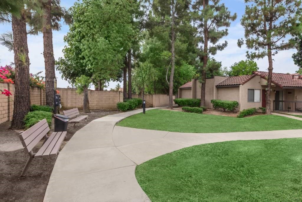 a park with a sidewalk and benches in front of a house