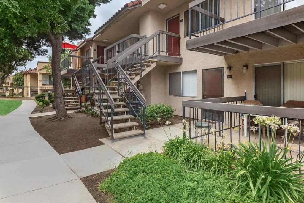 an apartment building with stairs and a sidewalk